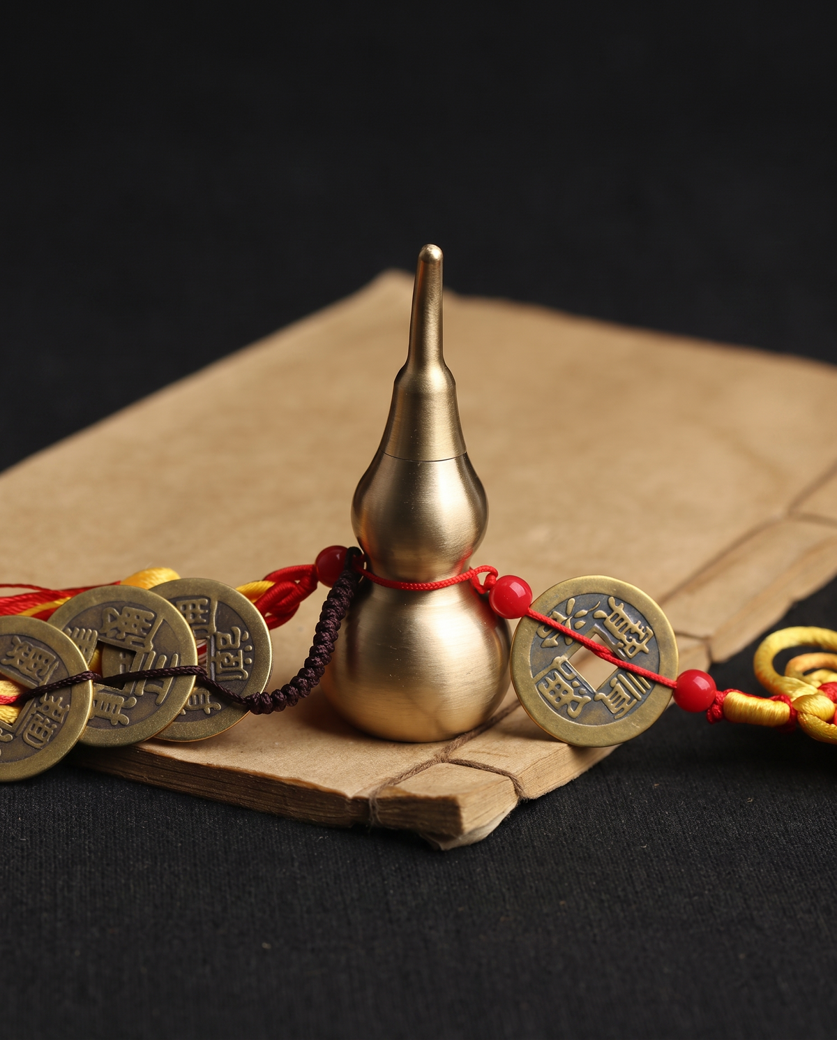 Brass hulu with five emperor coins on paper