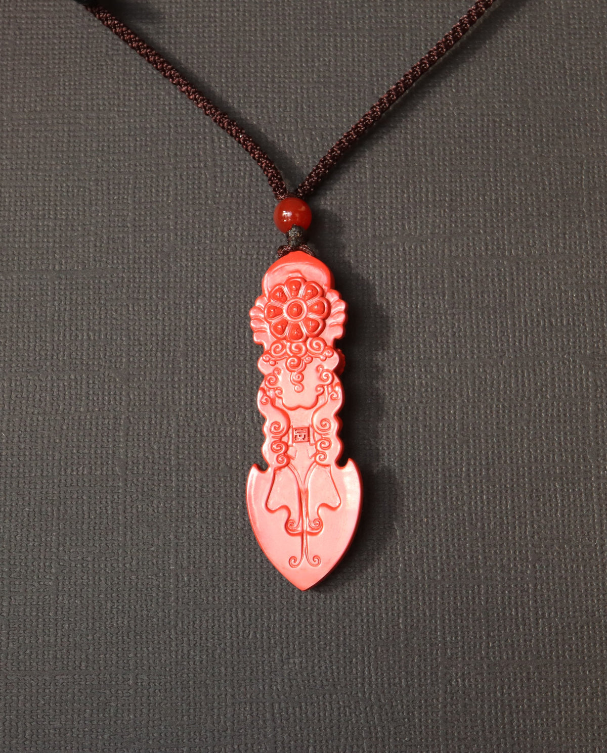 Guan Yin Phurba cinnabar necklace on dark background