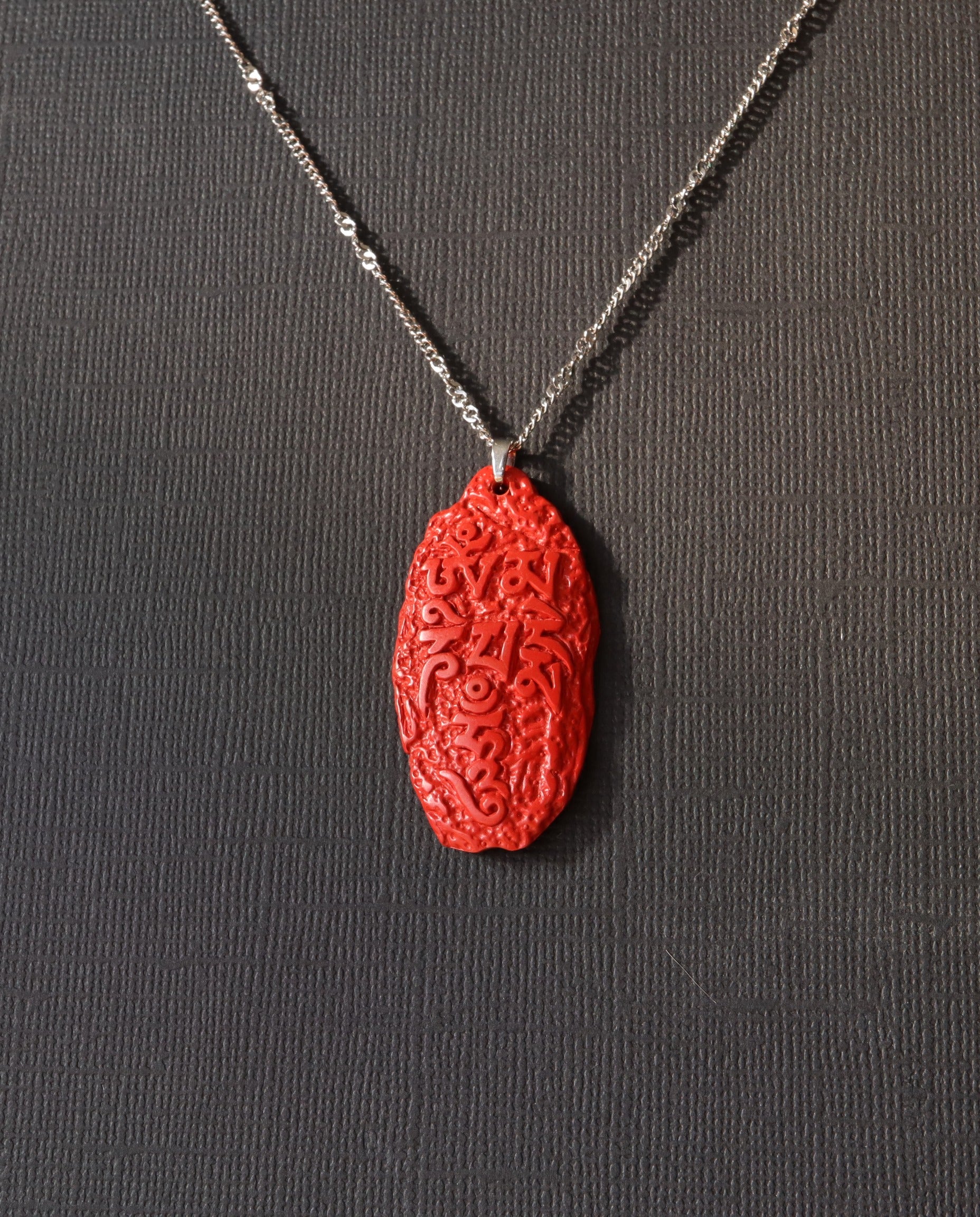 Six Character Mantra cinnabar necklace on dark background